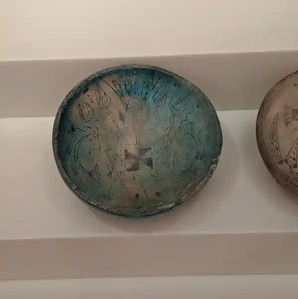 Bowls decorated with fish and floral motifs, and a swastika-like cross design at the center.